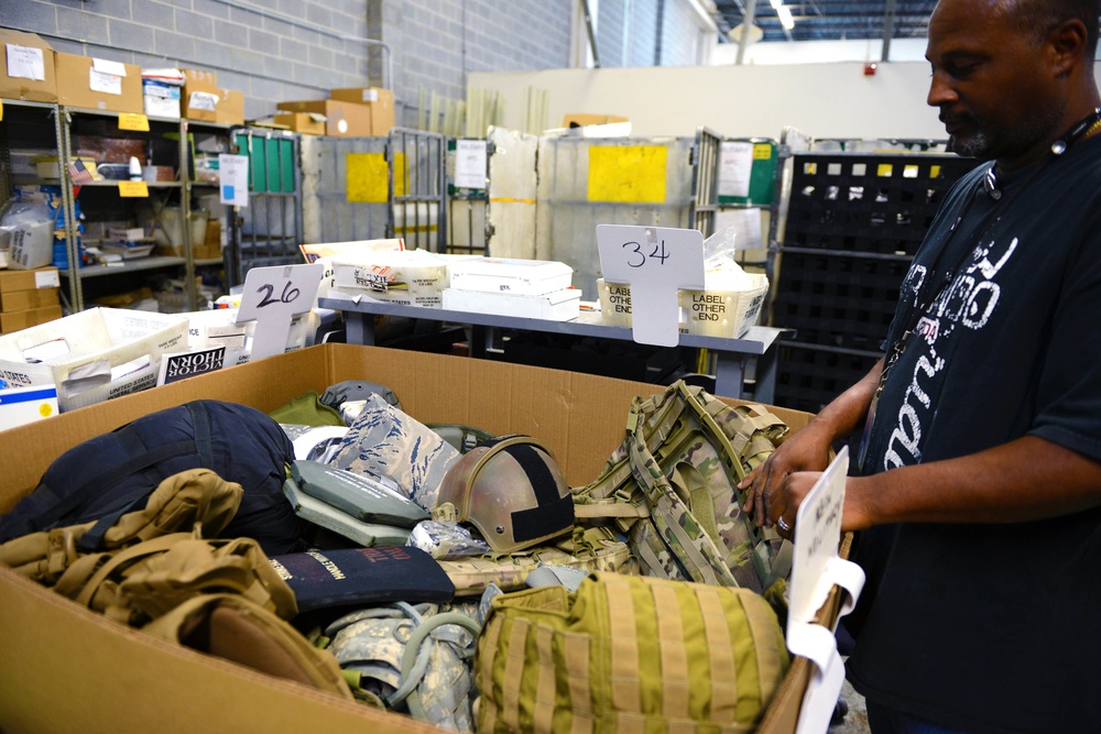 Postal Worker Examines Lost Military Equipment for Return to Defense Department