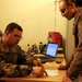 Air Force Tech. Sgt. Explains In-Processing to Visiting Service Member in Afghanistan