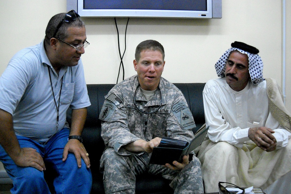 Army Officer, Iraqi Sheik, and Interpreter Discuss Photos in Iraq
