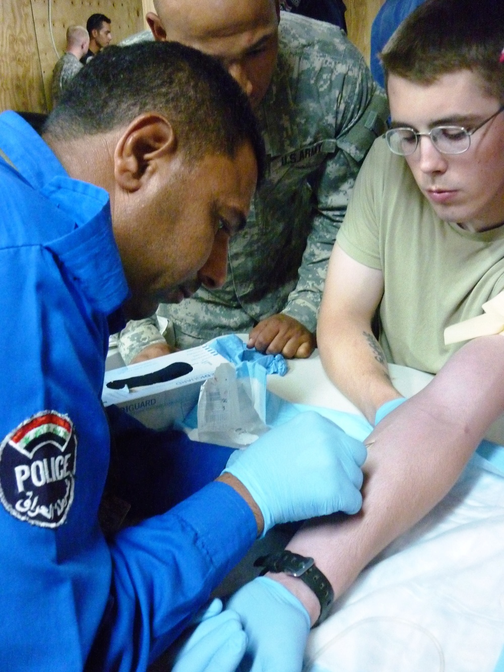 Iraqi Police Officer Practices IV Insertion Under Watchful Eyes of U.S. Army Medics