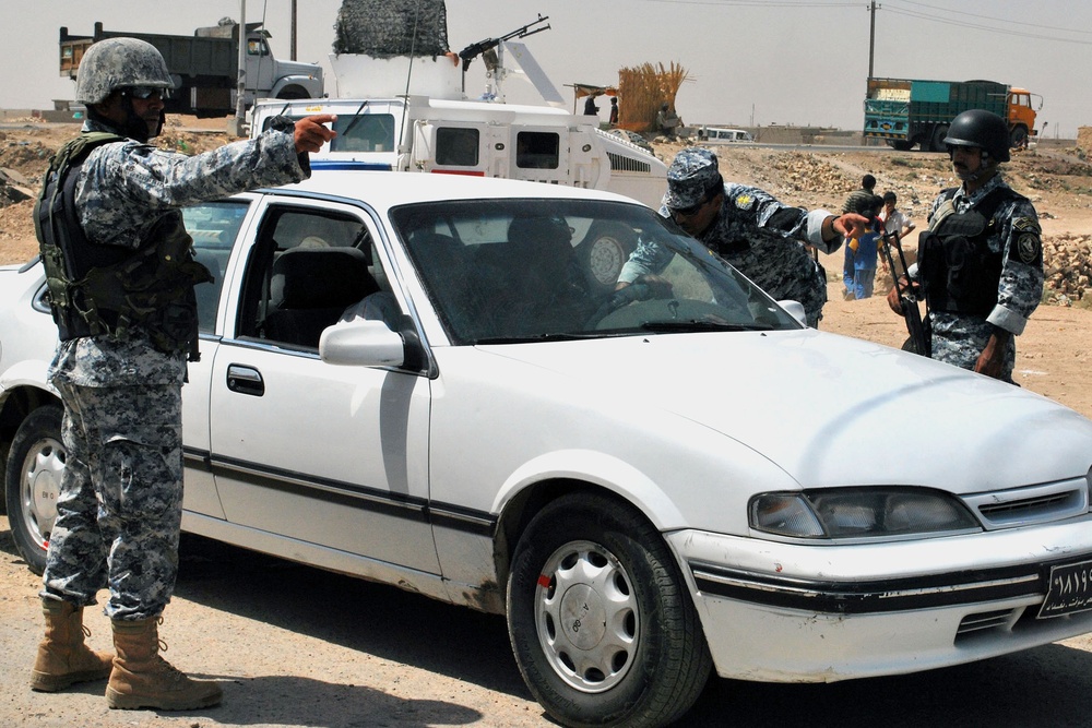 Iraqi Federal Police Conduct Vehicle Search at Checkpoint Near Baghdad