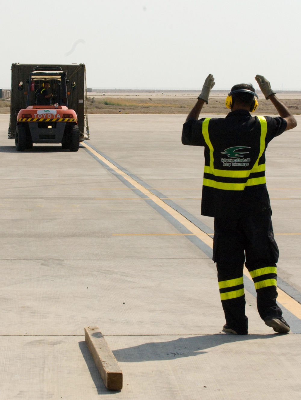 Iraqi Worker Guides Vehicle Across Basra Airport Tarmac