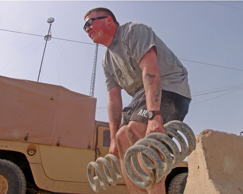 Soldier Lifts Humvee Springs in Fitness Training at Iraqi Base