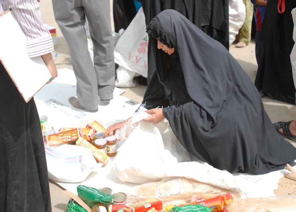 Iraqi Woman Receives Food Aid from National Police in Taji