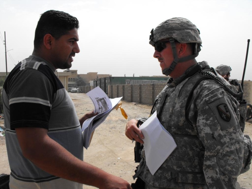 U.S. Soldier and Iraqi Contractor Discuss Wall Construction Project in Baghdad