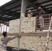 Iraqi Worker Tosses Brick During School Supply Warehouse Construction in Baghdad