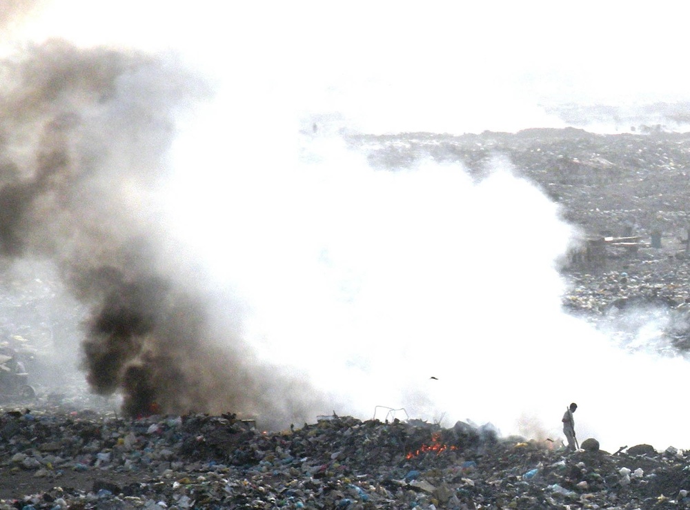 Iraqi Man Burns Garbage to Compact Landfill in Baghdad