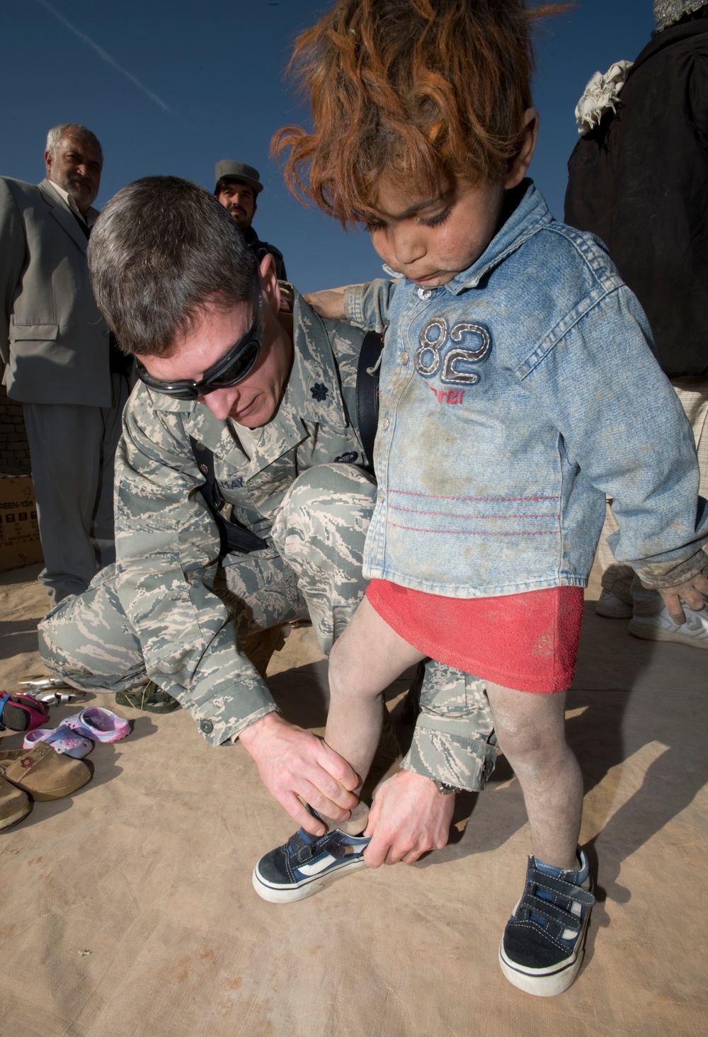 Air Force Doctor Helps Afghan Girl Try on Donated Shoes at Refugee Camp