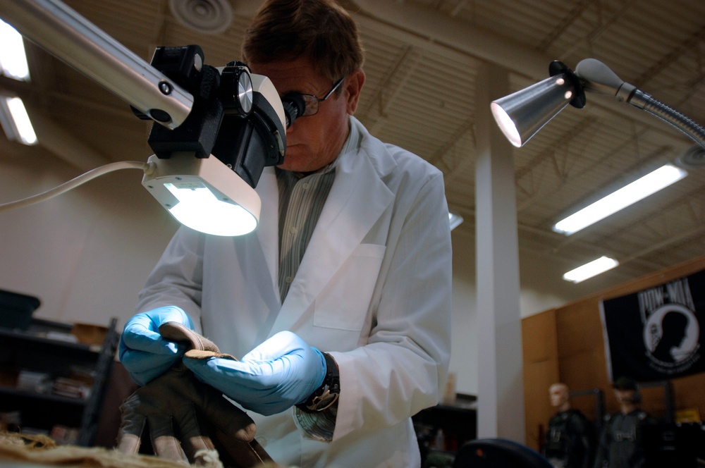 Equipment Analyst Inspects Glove Sample from Aircraft Crash Site