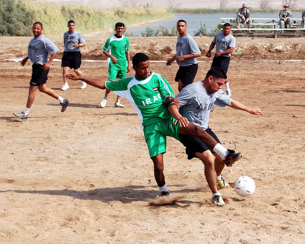 U.S. Soldier Competes for Soccer Ball with Iraqi Counterpart