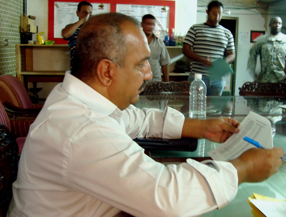 Sons of Iraq Leader Reviews Documents During Registration