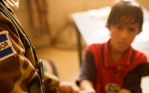 Salvadoran Officer Examines Iraqi Boy's Hands During Medical Mission in Kut