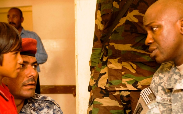 Army Captain Engages with Iraqi Policeman and Boy During Medical Outreach in Kut