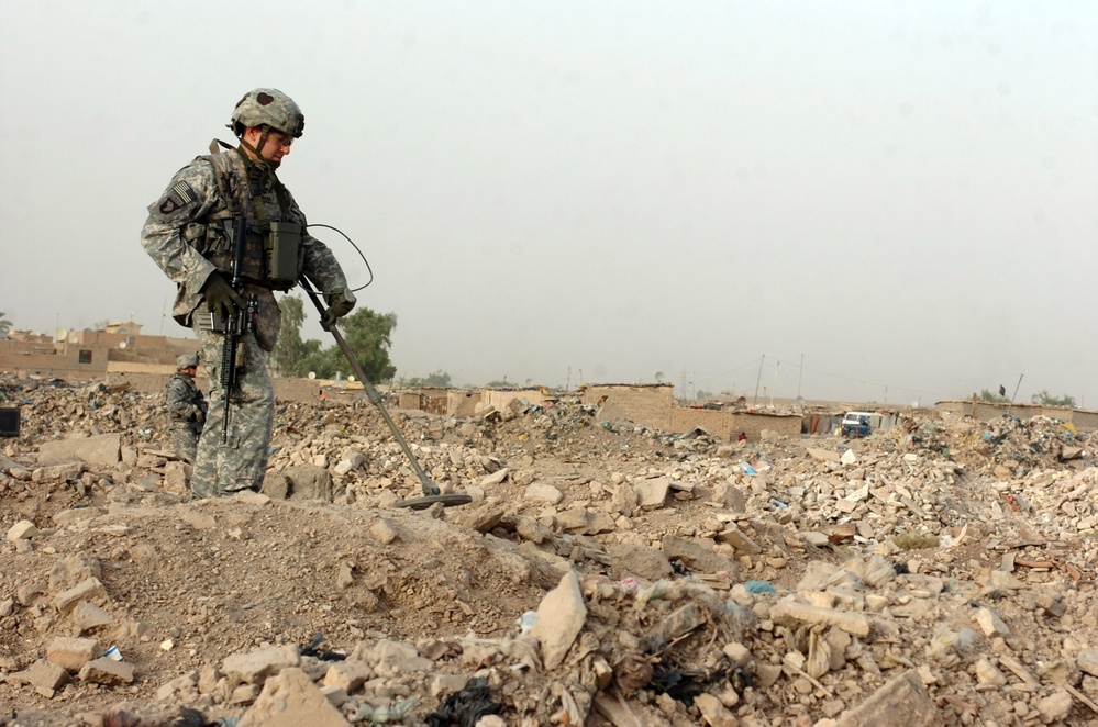 Soldier Searches for Enemy Caches in Iraqi Field