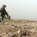 Soldier Searches for Enemy Caches in Iraqi Field