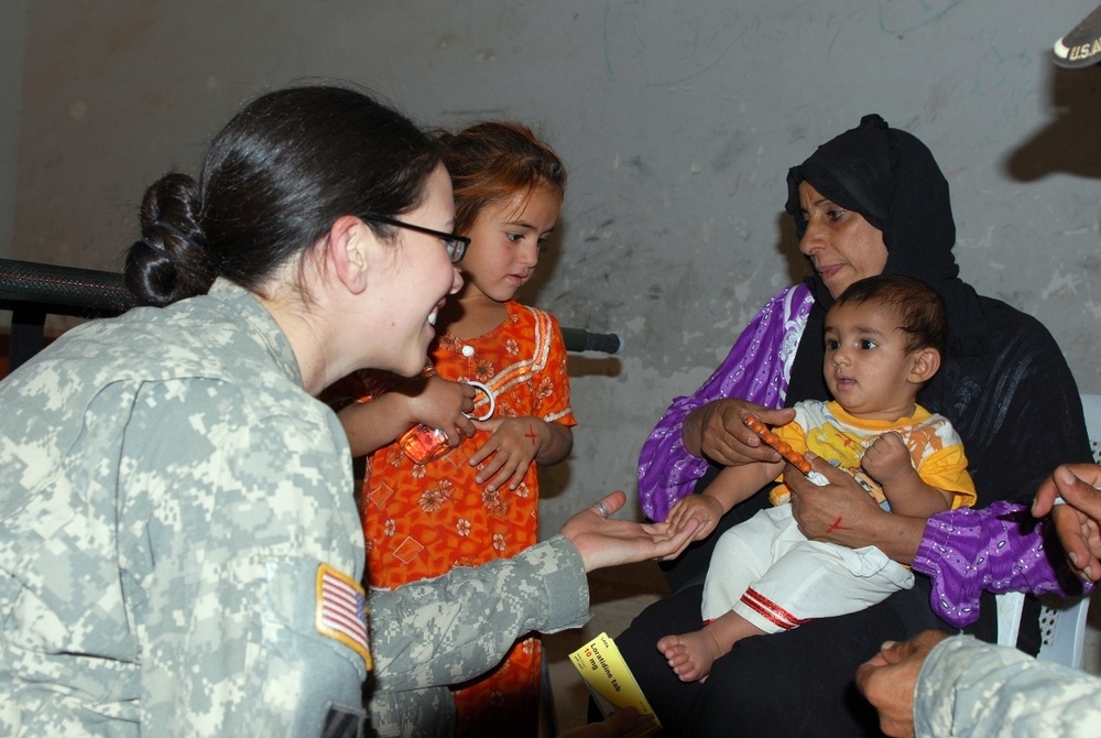 Army Medic Comforts Iraqi Child During Medical Engagement