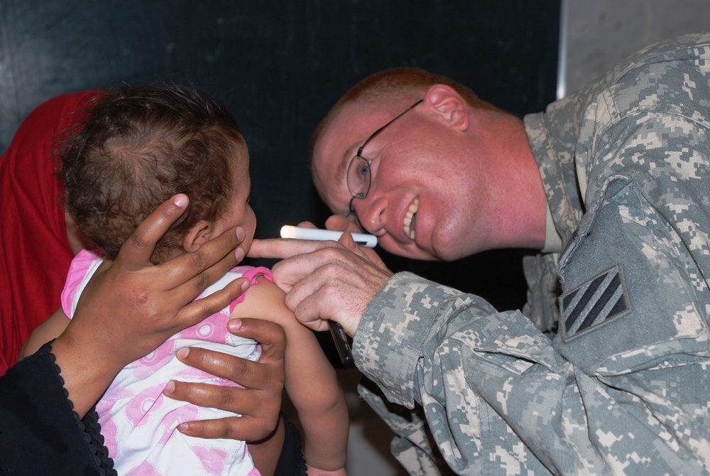 Army Medic Examines Child's Mouth During Medical Engagement
