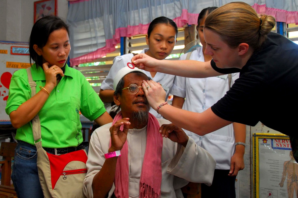 Air Force Airman Assists Patient with Glasses During Medical Mission in Philippines