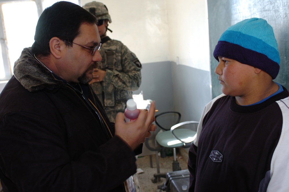 Iraqi Pharmacist Provides Medication Guidance to Boy During Medical Operation
