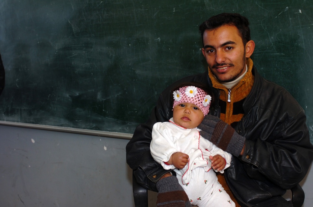 Iraqi Father Holds Infant Before Medical Exam in Baghdad
