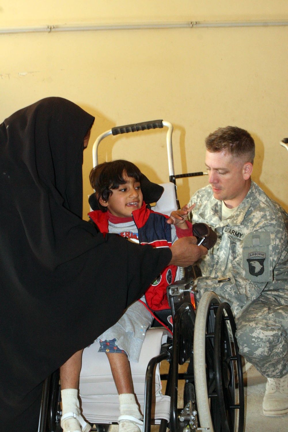 U.S. Army Medic Assists Iraqi Civilian with Wheelchair Adjustments