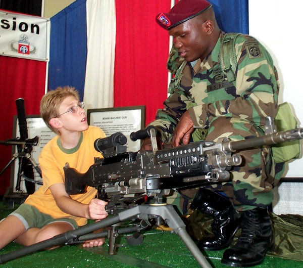 Young Boy Learns About Army Weaponry at Public Service Event