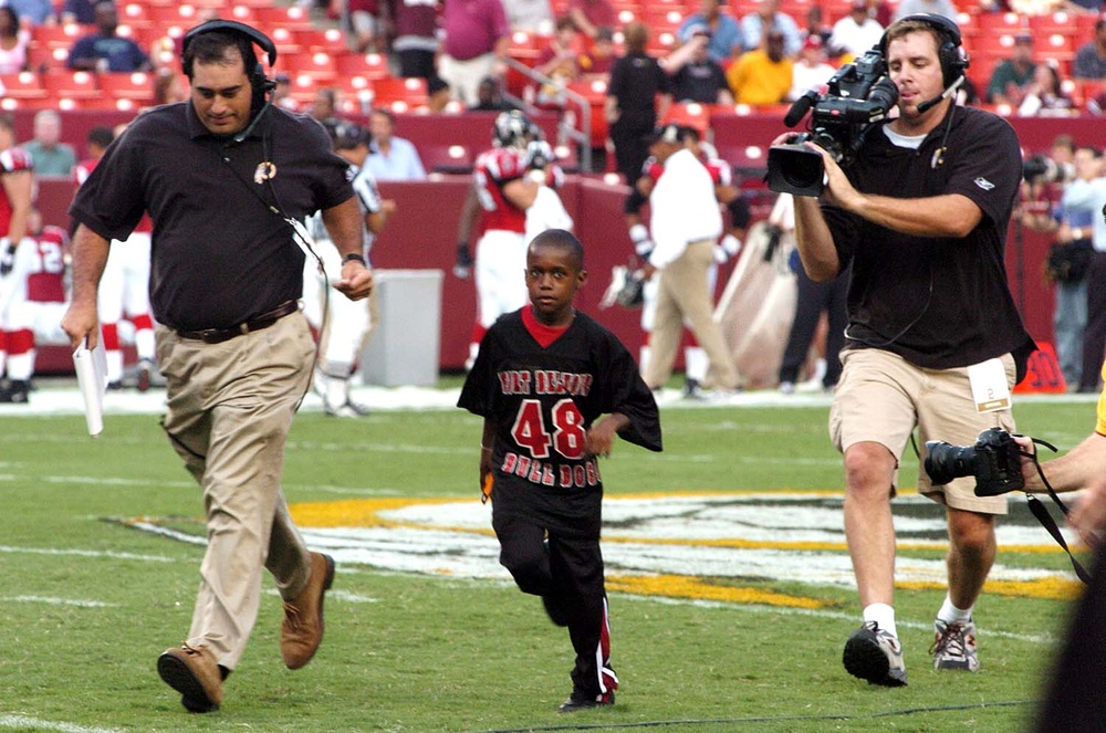 Young Footballer Participates in Coin Toss at NFL Exhibition Game