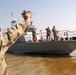 Servicemember Waves Farewell as Fast Boat Departs Umm Qasr Port