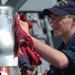 Crewmember Polishes Ship's Bell Aboard USS James E. Williams