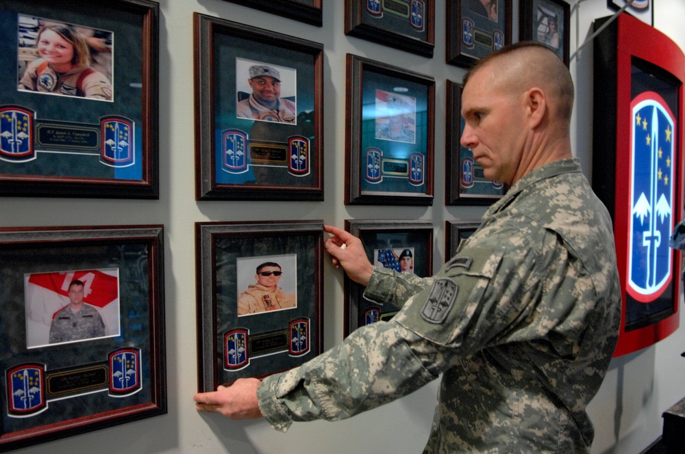 Honoring the Fallen: Sgt. 1st Class Straightens Portrait at Memorial Wall Dedication