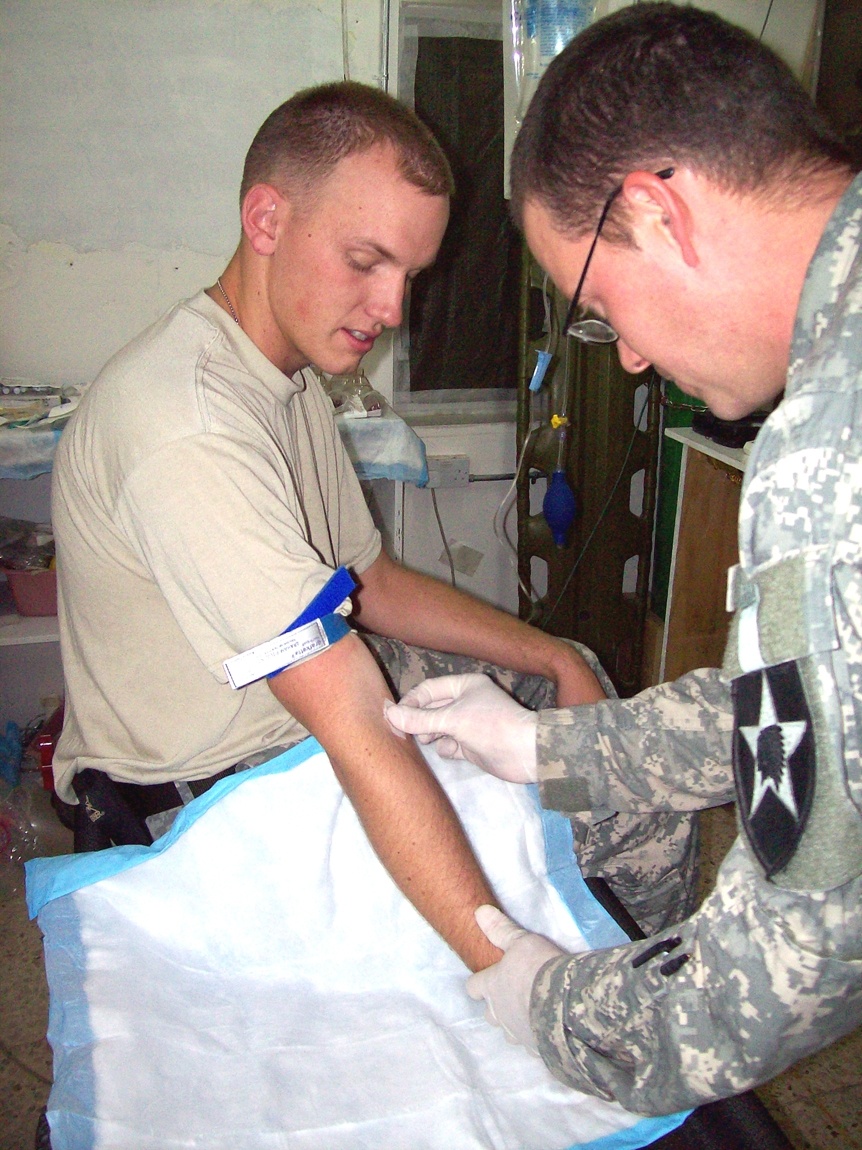 Army Medic Administers IV to Soldier at Forward Operating Base in Iraq