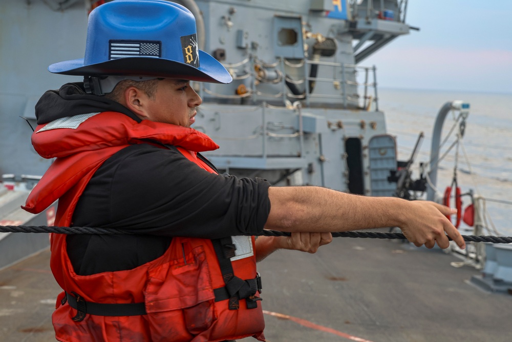 STG3 Iyan Rosales heaves on a phone and distance line during a COMPTUEX replenishment-at-sea