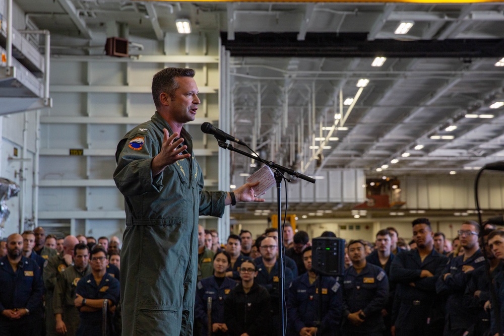 Abraham Lincoln conducts an all-hands call in the hangar bay