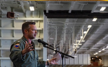 Abraham Lincoln conducts an all-hands call in the hangar bay