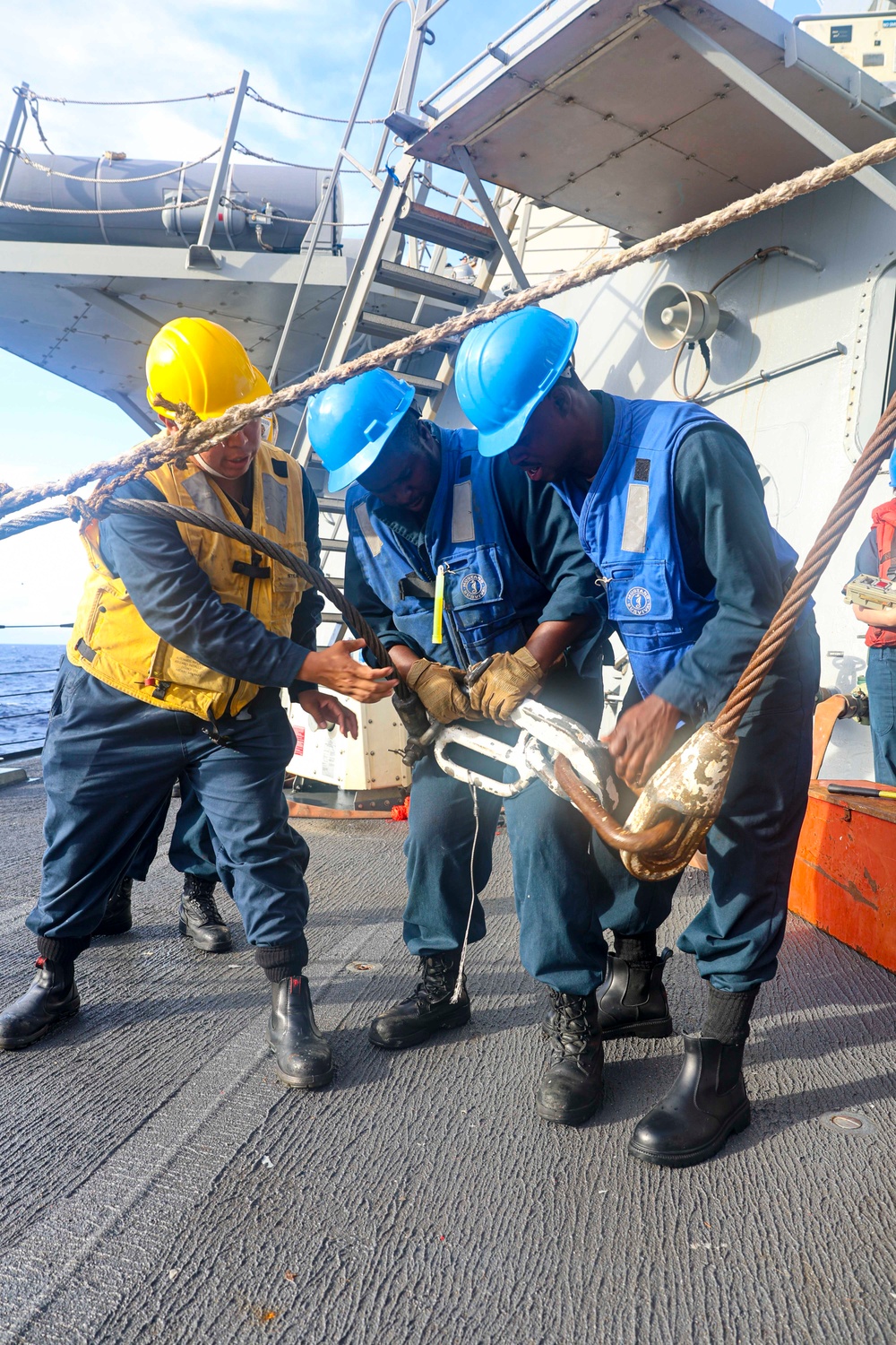 BM2 Kanim Hannigan, BMSN William Mwiseneza and BM3 Carlens Milice connect the surf hook to the tensioning line