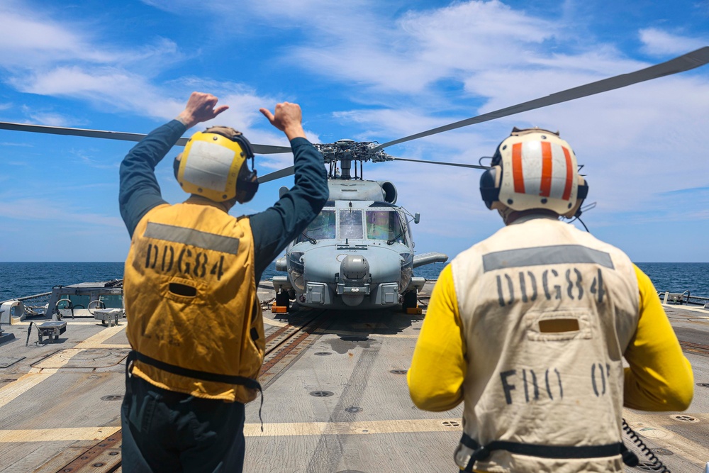 BM1  Jason Carpenter and BM1 Youssef Belakbir signal the pilots of the MH-60S Seahawk