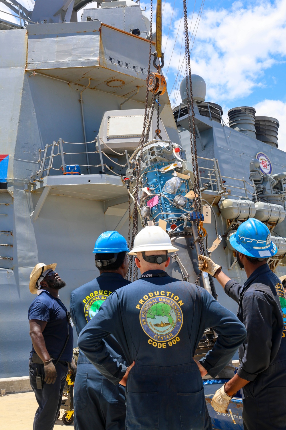 Sailors  and contractors connect an Allison gas turbine generator to a crane hoist