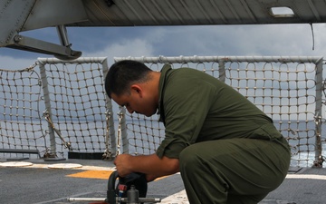 Sailors aboard the USS John Finn conduct routine maintenance on an MH-60R Sea Hawk in the Strait of Malacca
