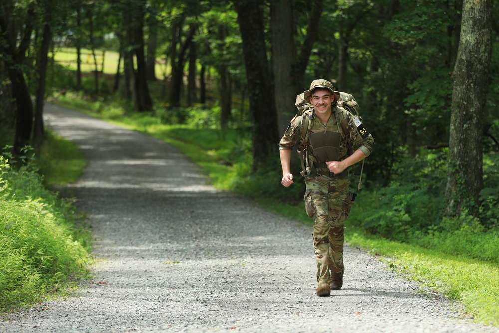 Spc. Adam Andrews runs with rucksack in river operations - 2025 National Best Warrior