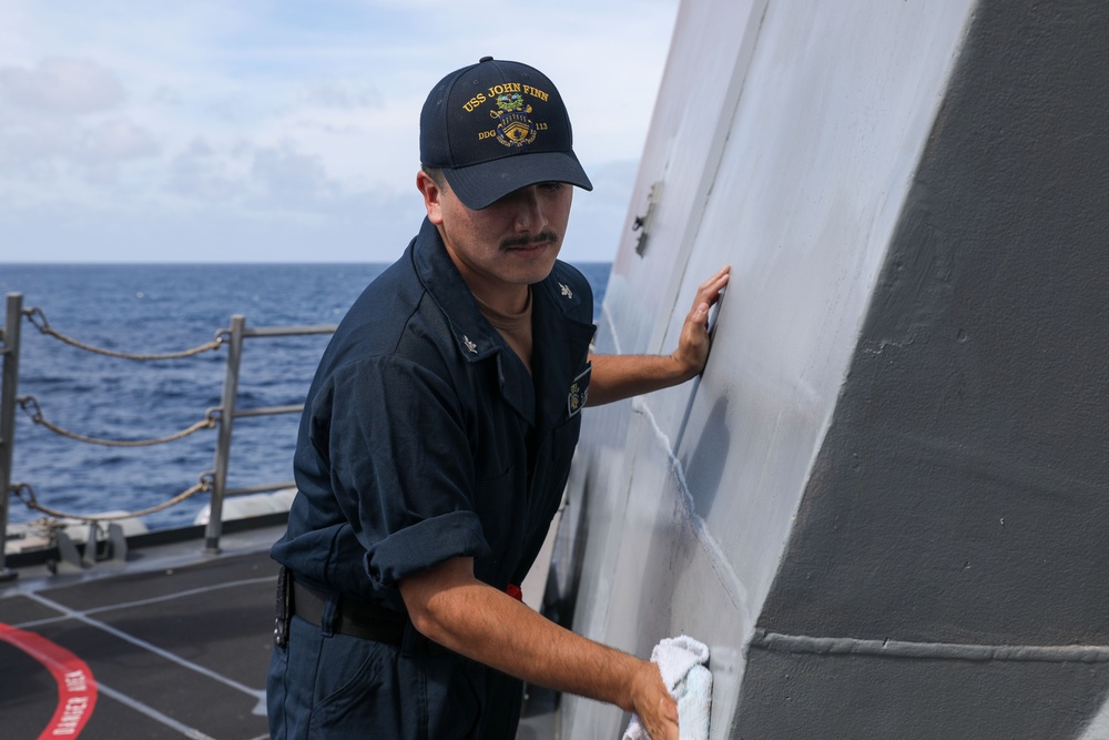 Sailors aboard the USS John Finn conduct topside preservation efforts in the Indian Ocean