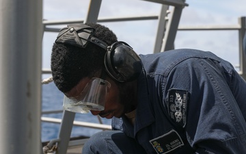 Sailors aboard the USS John Finn conduct topside preservation efforts in the Indian Ocean