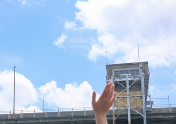 Midshipman Ashley Sarno waves to Coleman Memorial Bridge personnel from the portside bridge wing