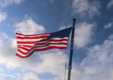 USS Bulkeley Sailors salute the ensign during morning colors on the aft flight deck