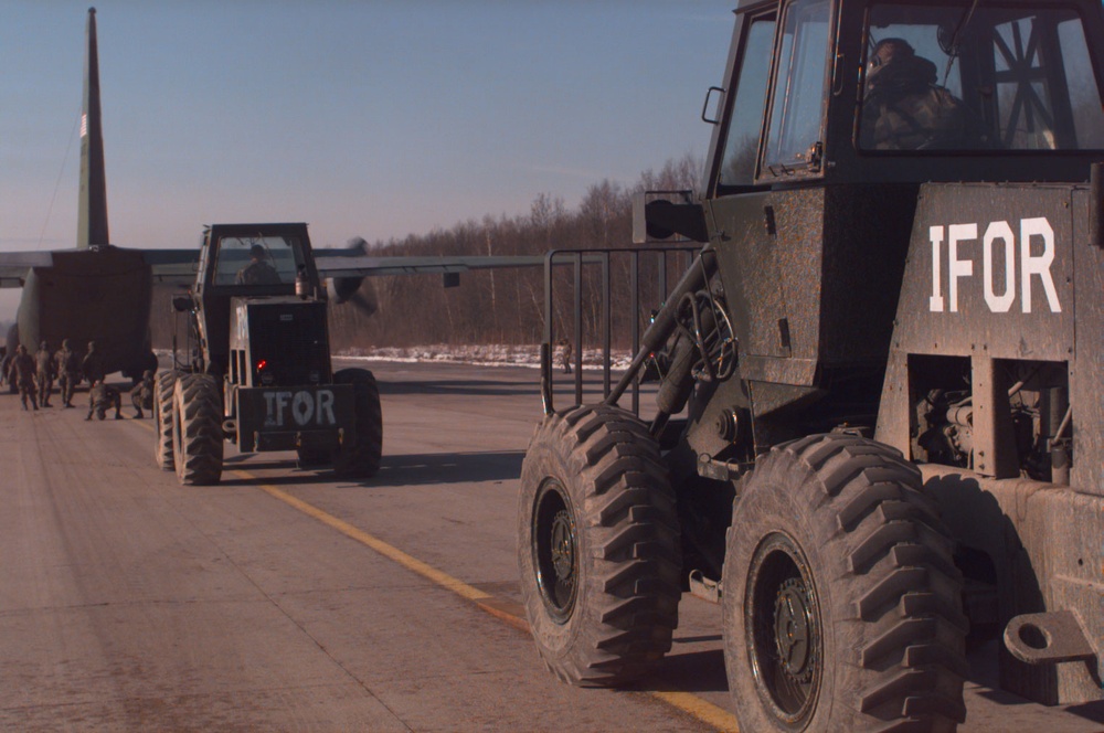 NATO Implementation Force (IFOR) forklifts line up to unload a C-130 Hercules