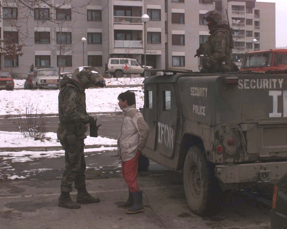 U.S. Air Force security policeman digs in his pockets for candy for a boy in Tuzla, Bosnia and Herzegovina.