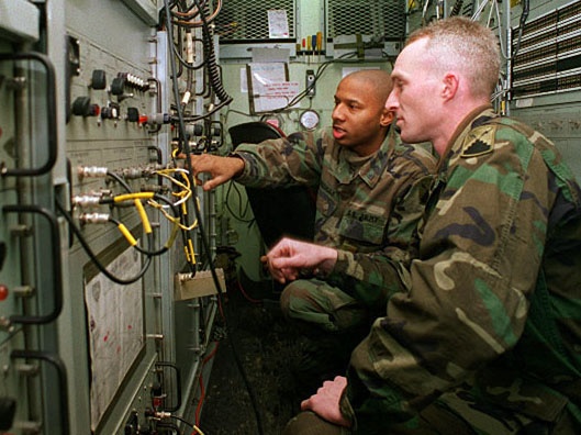 U.S. Army soldiers work in a AN/TSC-85B satellite communications terminal van.