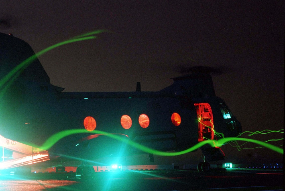 A CH-46 Sea Knight is readied for night launch from the USS Nassau.