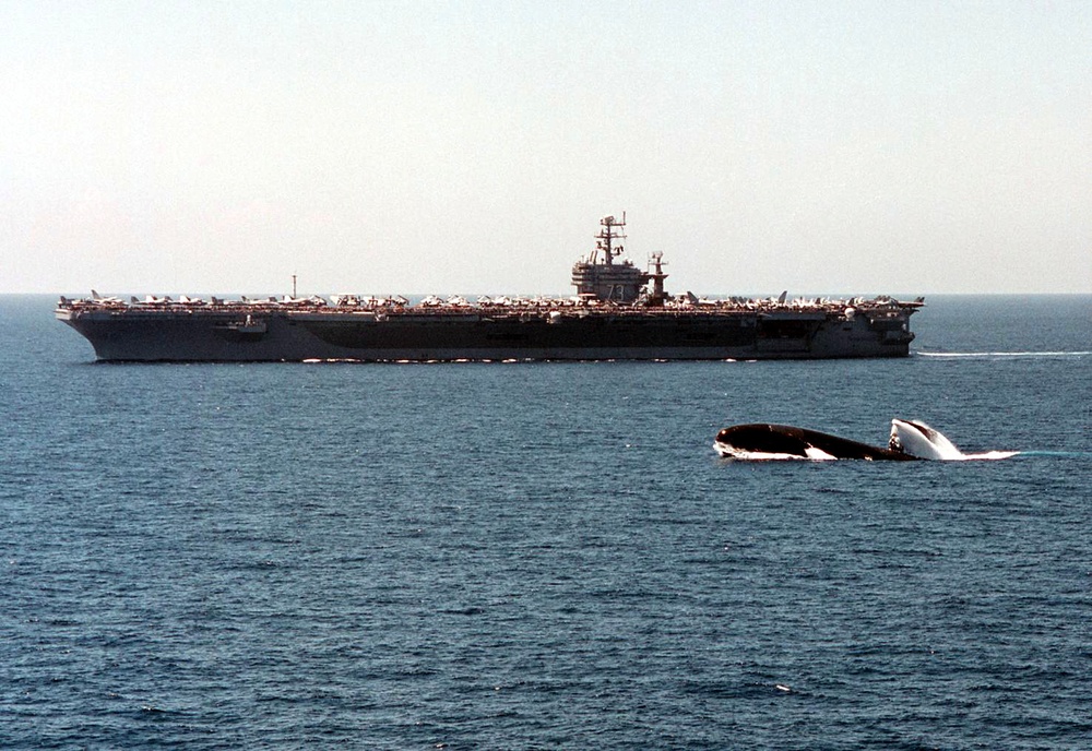 The submarine USS Scranton surfaces alongside the USS George Washington.