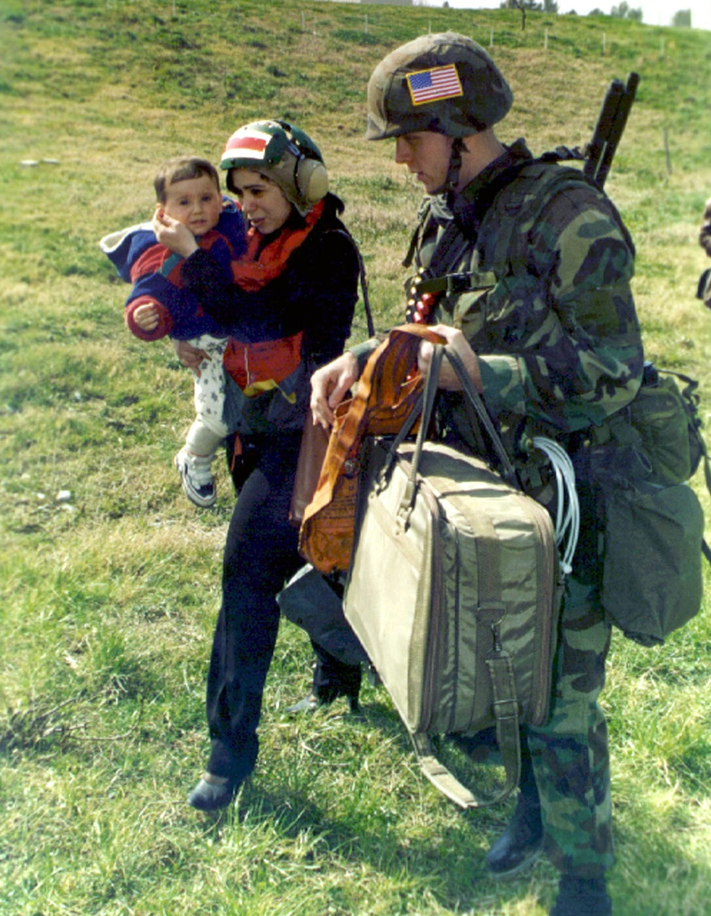 Military Policeman escorts a woman and her child to a waiting helicopter at Tirana, Albania.