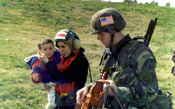 Military Policeman escorts a woman and her child to a waiting helicopter at Tirana, Albania.